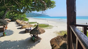 A beachside area with thatched-roof huts and a wooden deck overlooking the beach. - Havelock Harmony Resort (Port Blair)