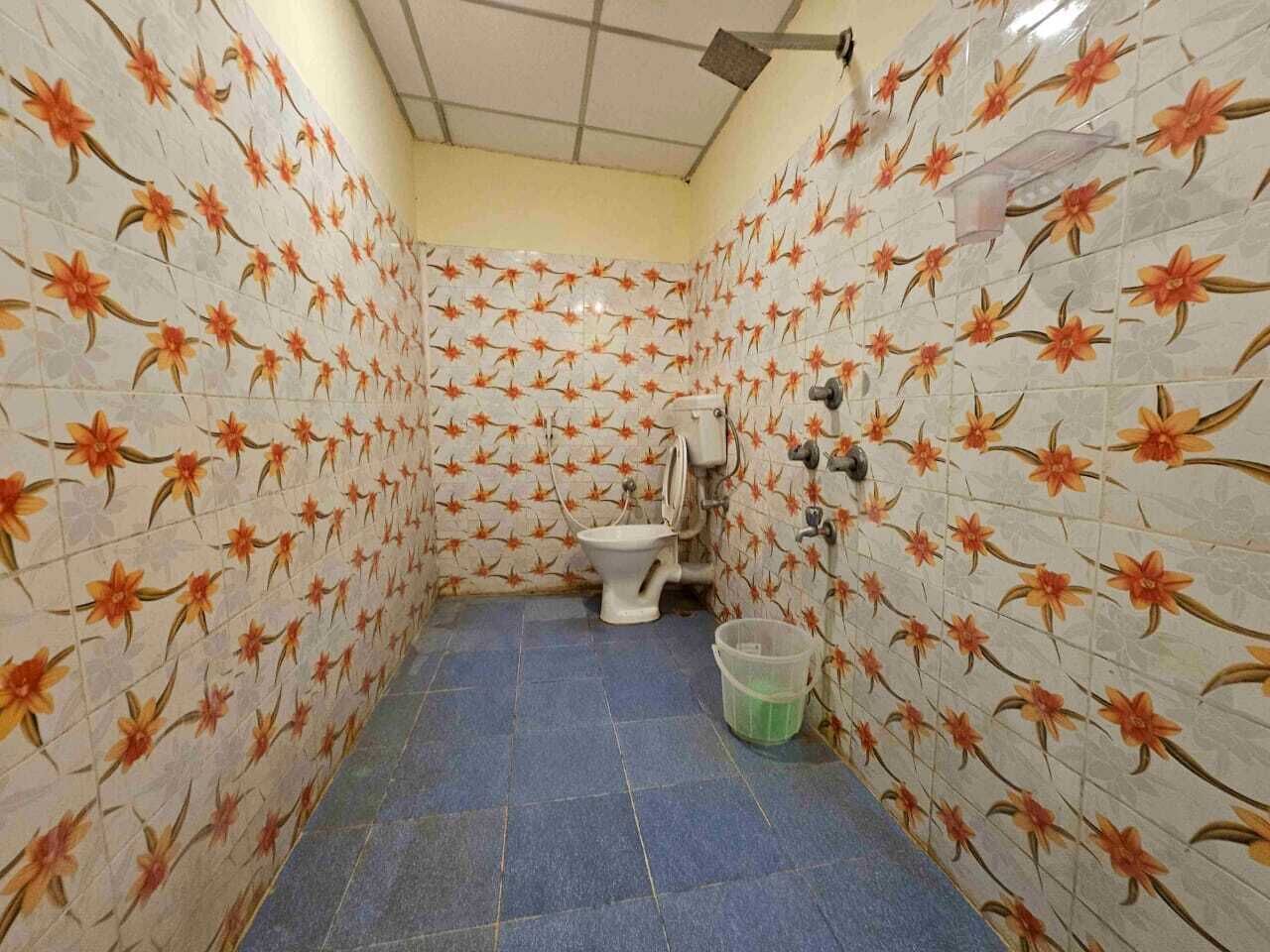 A small bathroom with floral-patterned tiles, a toilet, and a blue floor.