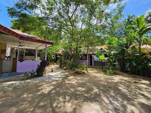 A courtyard with a covered seating area, surrounded by lush greenery and trees. - Havelock Harmony Resort (Port Blair)