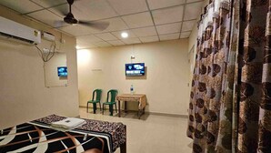 A hotel room with a bed, a desk, two chairs, a television, and a curtain. - Havelock Harmony Resort (Port Blair)