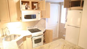 A kitchen with a built-in oven, microwave, and stainless steel sink. - The Secret In the Springs Hideaway, a luxury efficiency at the Legacy Trail (Sarasota)