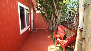 A red wooden building with a covered porch, a red chair, and a small table. - The Secret In the Springs Hideaway, a luxury efficiency at the Legacy Trail (Sarasota)