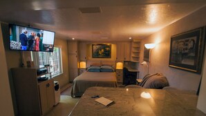 A hotel room with a bed, a desk, a television, and a painting on the wall. - The Secret In the Springs Hideaway, a luxury efficiency at the Legacy Trail (Sarasota)