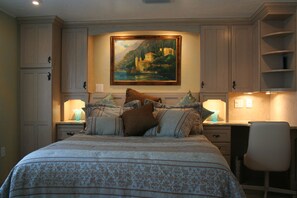 A bedroom with a large bed, a desk, and a chair. There is a painting on the wall above the bed. - The Secret In the Springs Hideaway, a luxury efficiency at the Legacy Trail (Sarasota)