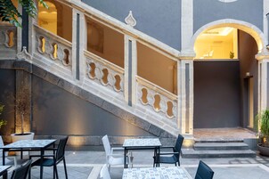Un cortile con posti a sedere all'aperto, una scala in pietra e l'ingresso di un edificio.