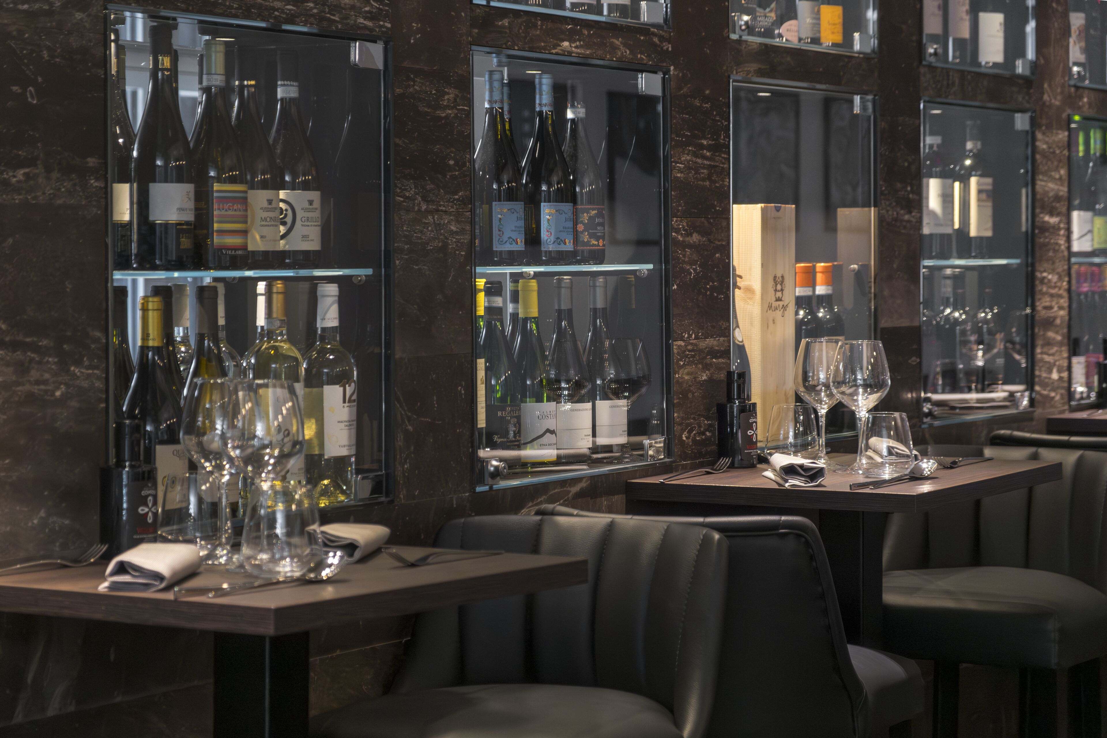 Interior de un restaurante con varias mesas, cada una dispuesta con copas y botellas de vino.
