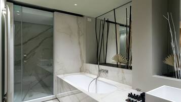 Un bagno moderno con cabina doccia in vetro, una vasca da bagno in marmo e un mobile lavabo con articoli da toilette.