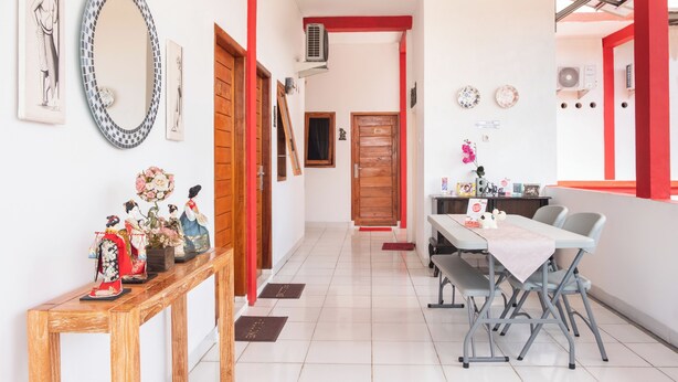 A hallway with a wooden bench, a table with chairs, and a dining area with a table and chairs. - OYO 2919 Andung Residence (Bandar Lampung)