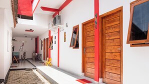 A narrow corridor with tiled flooring, wooden doors, and a small seating area with a yellow chair. - OYO 2919 Andung Residence (Bandar Lampung)