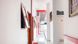 A hallway with red and white walls, a tiled floor, and a staircase with a red handrail. - OYO 2919 Andung Residence (Bandar Lampung)