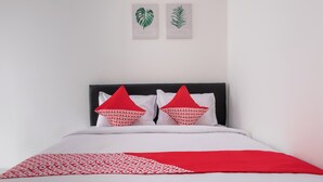 A bed with a white and red bedspread, two red pillows with white text, and two framed botanical prints on the wall. - OYO 2919 Andung Residence (Bandar Lampung)