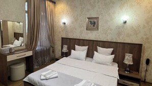 A neatly arranged bedroom with a large bed, bedside tables, a mirror, and a ceiling light fixture. - SANAPIRO (Tbilisi)