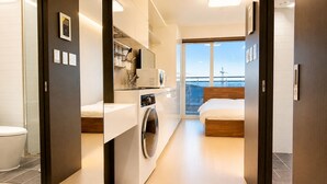 A modern hotel room with a washing machine, a bed, a balcony with a view, and a large window. - Yeongjong Shine Hotel (Incheon)