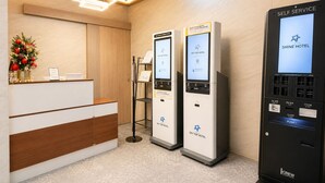 A hotel reception area with a wooden reception desk, two self-service kiosks, and a self-service machine. - Yeongjong Shine Hotel (Incheon)