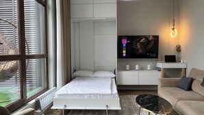 Un dormitorio moderno con una cama, televisor, escritorio y sofá.