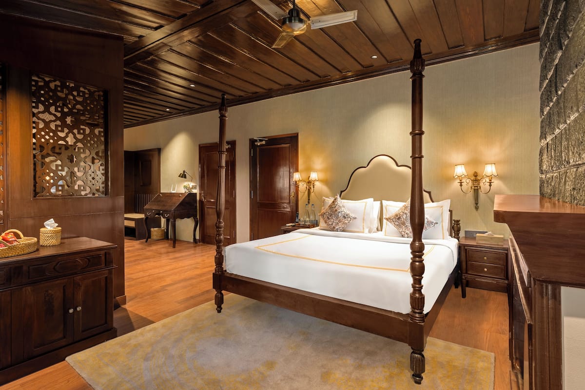 A four-poster bed with a wooden frame, a large mirror, and a decorative wall panel.