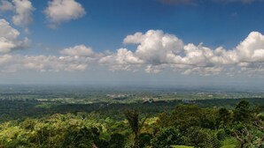 Una vista panorámica de un paisaje exuberante y verde, con cielo despejado y algunas nubes dispersas.
