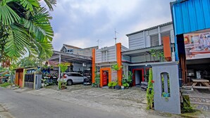 A commercial building with multiple storefronts, including a restaurant with outdoor seating. - OYO 3012 Coupis Guesthouse Syariah (Pare)