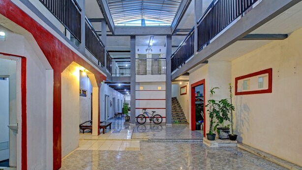 A spacious indoor area with a high ceiling, a staircase, and a bicycle. - OYO 3012 Coupis Guesthouse Syariah (Pare)