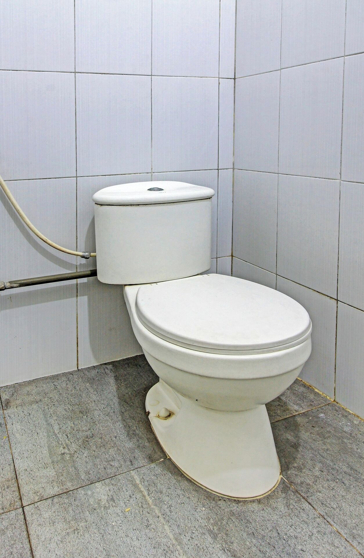A standard white toilet in a bathroom with tiled walls and a tiled floor.