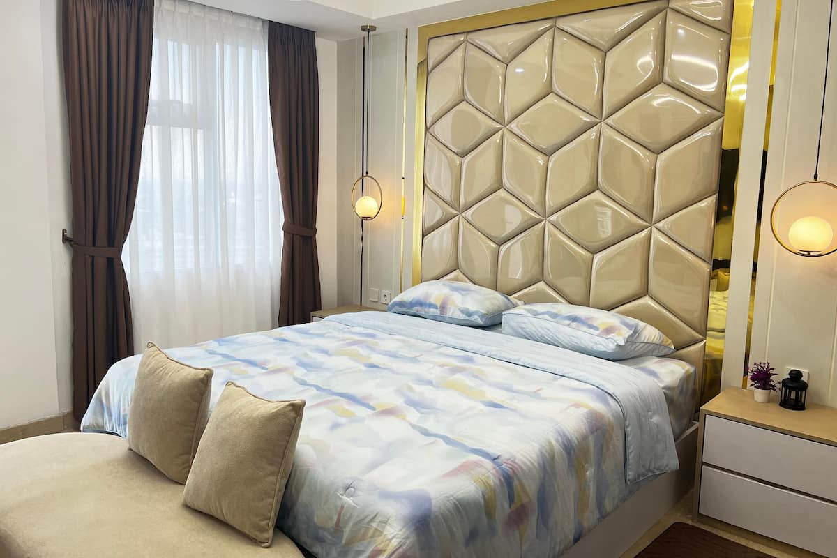 Ein modernes Schlafzimmer mit einem großen Bett, einem Kopfteil mit geometrischem Muster, Nachttischlampen und einem Nachttisch mit einer kleinen Pflanze.