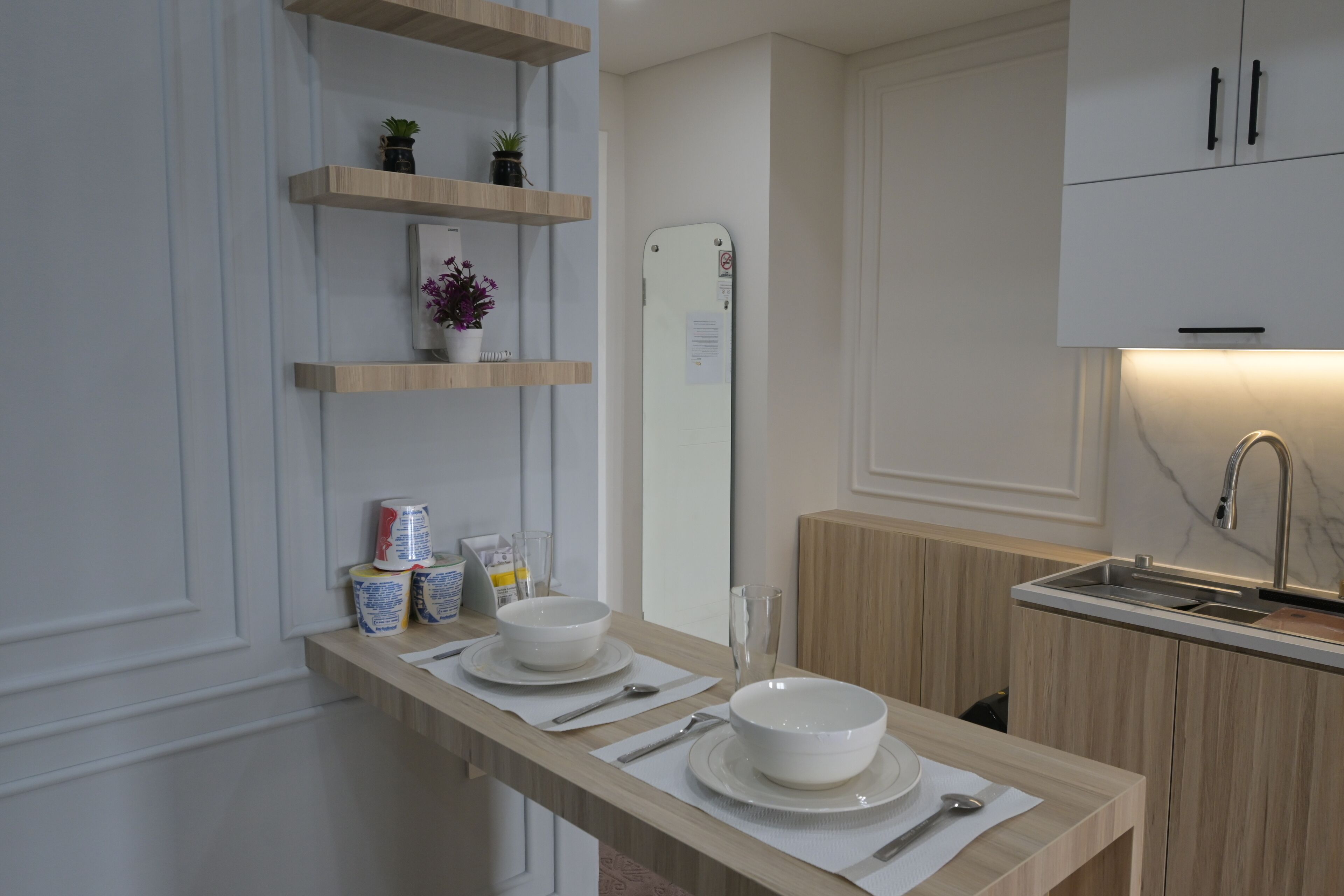 Una cocina moderna con armarios de madera, un lavamanos integrado y una encimera con cuencos, platos y utensilios.