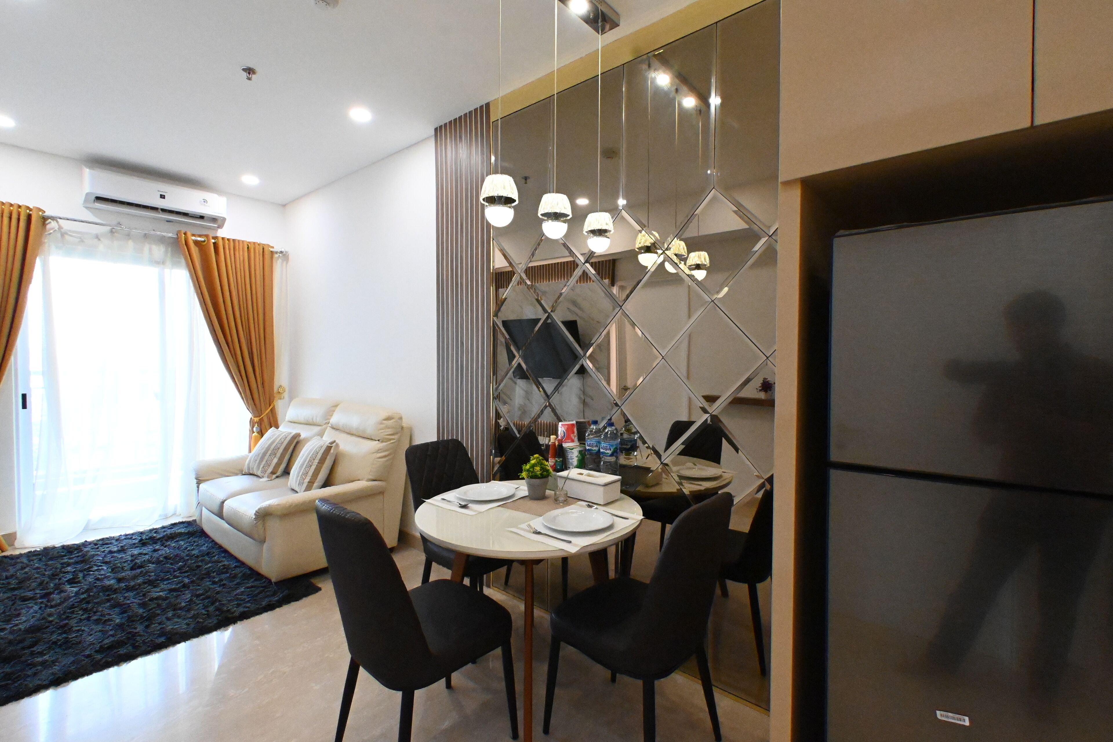 Una sala de estar moderna con un sofá, una mesa de comedor, sillas y un espejo grande.