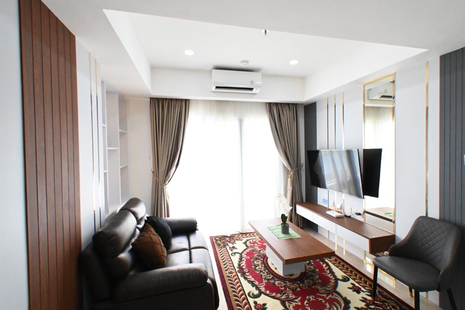 A modern living room with a sofa, armchair, TV, and a coffee table.