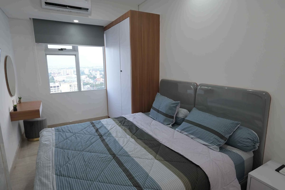 Ein Schlafzimmer mit Bett, Fenster, Kleiderschrank und Nachttisch.