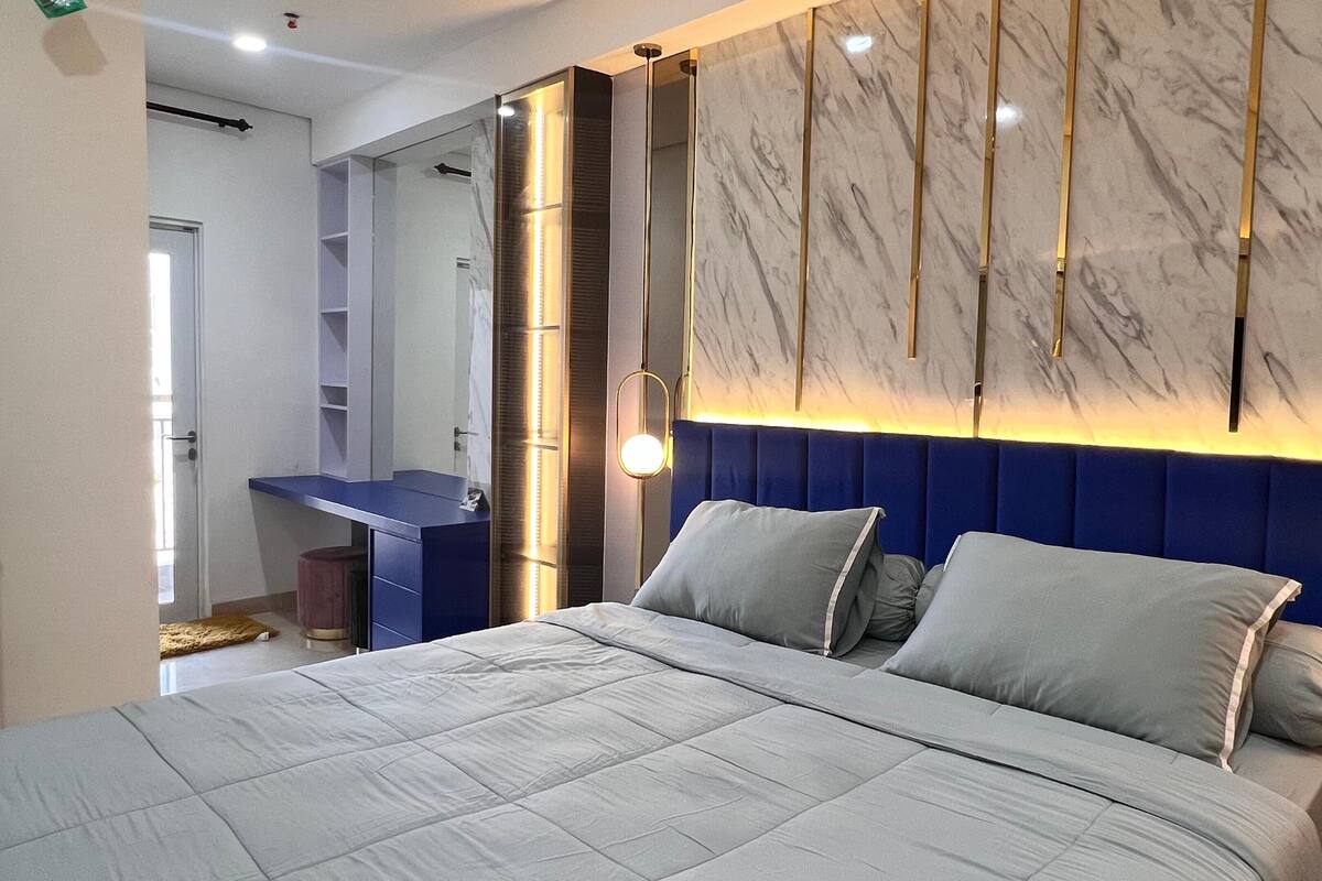 Ein modernes Schlafzimmer mit einem großen Bett, einem integrierten Schreibtisch und einer Wand mit Marmorverkleidung.