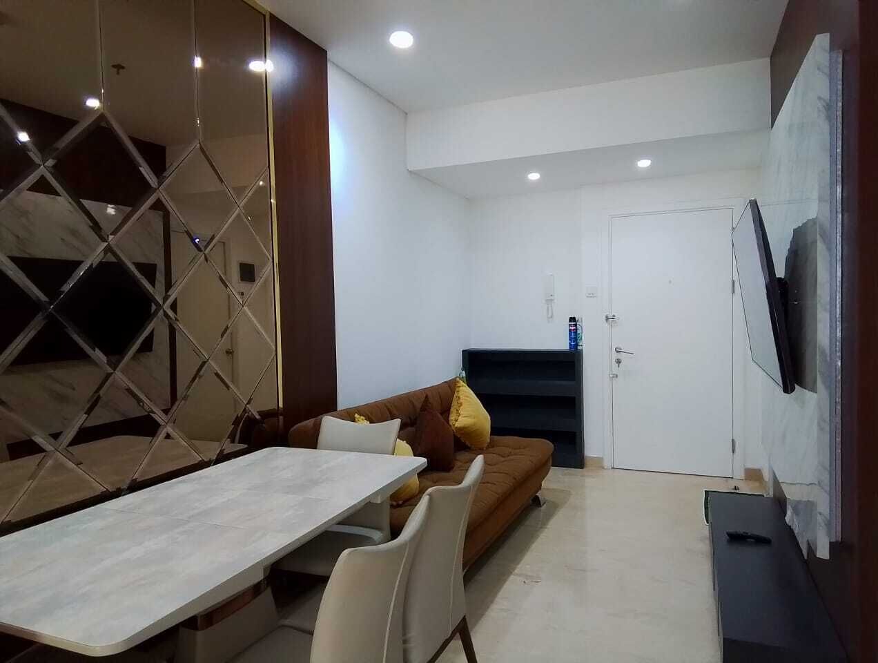 Ein modernes Wohnzimmer mit Essbereich, einer Couch, einem Fernseher und einer Tür.