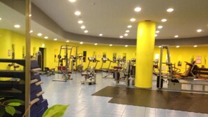 A gym with various exercise equipment, a yellow wall, and a tiled floor. - Olimpic Village TH Sestriere apartments x6 (Sestriere)