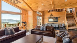 A spacious living area with a large window overlooking a scenic landscape, a fireplace, and a staircase leading to an upper level.