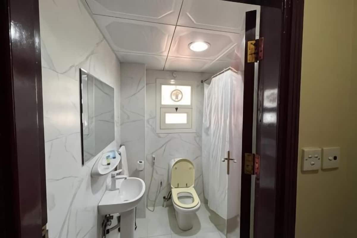 Une salle de bain avec des toilettes, un lavabo, un miroir et une fenêtre.