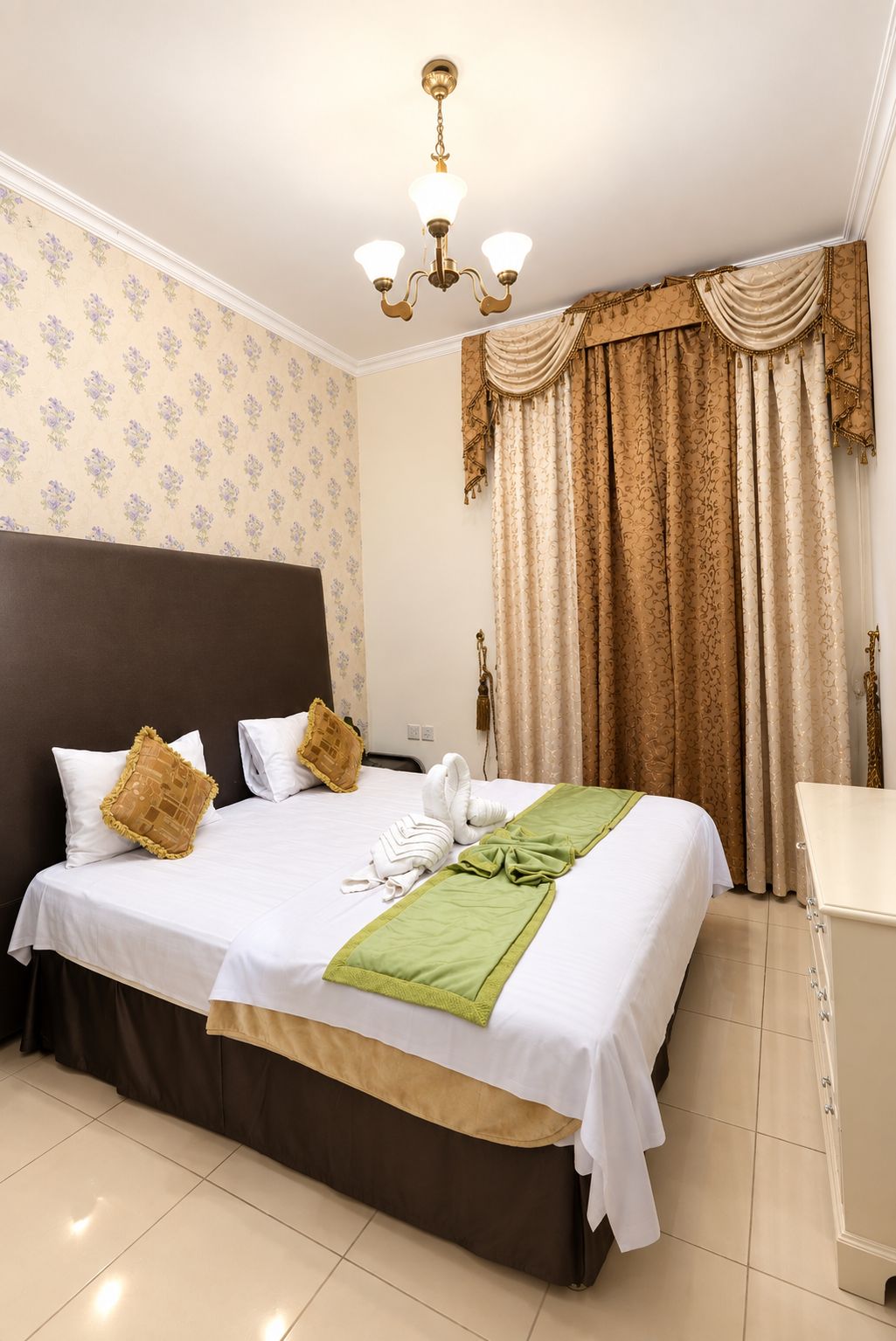 Een hotelkamer met een groot bed, een nachtkastje, een spiegel en een kroonluchter.