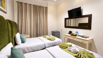 A hotel room with two beds, a desk with a television, and a mirror.