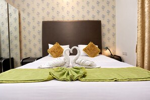 A hotel room with a neatly made bed, two pillows, a green throw blanket, and a headboard. - Al Jazeerah Hotel (Sharjah)