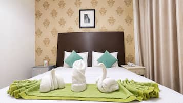 A hotel room with a neatly made bed, two pillows, a bedside table with a phone, and a framed picture on the wall.
