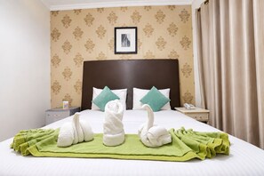 A hotel room with a neatly made bed, two pillows, a bedside table with a phone, and a framed picture on the wall. - Al Jazeerah Hotel (Sharjah)