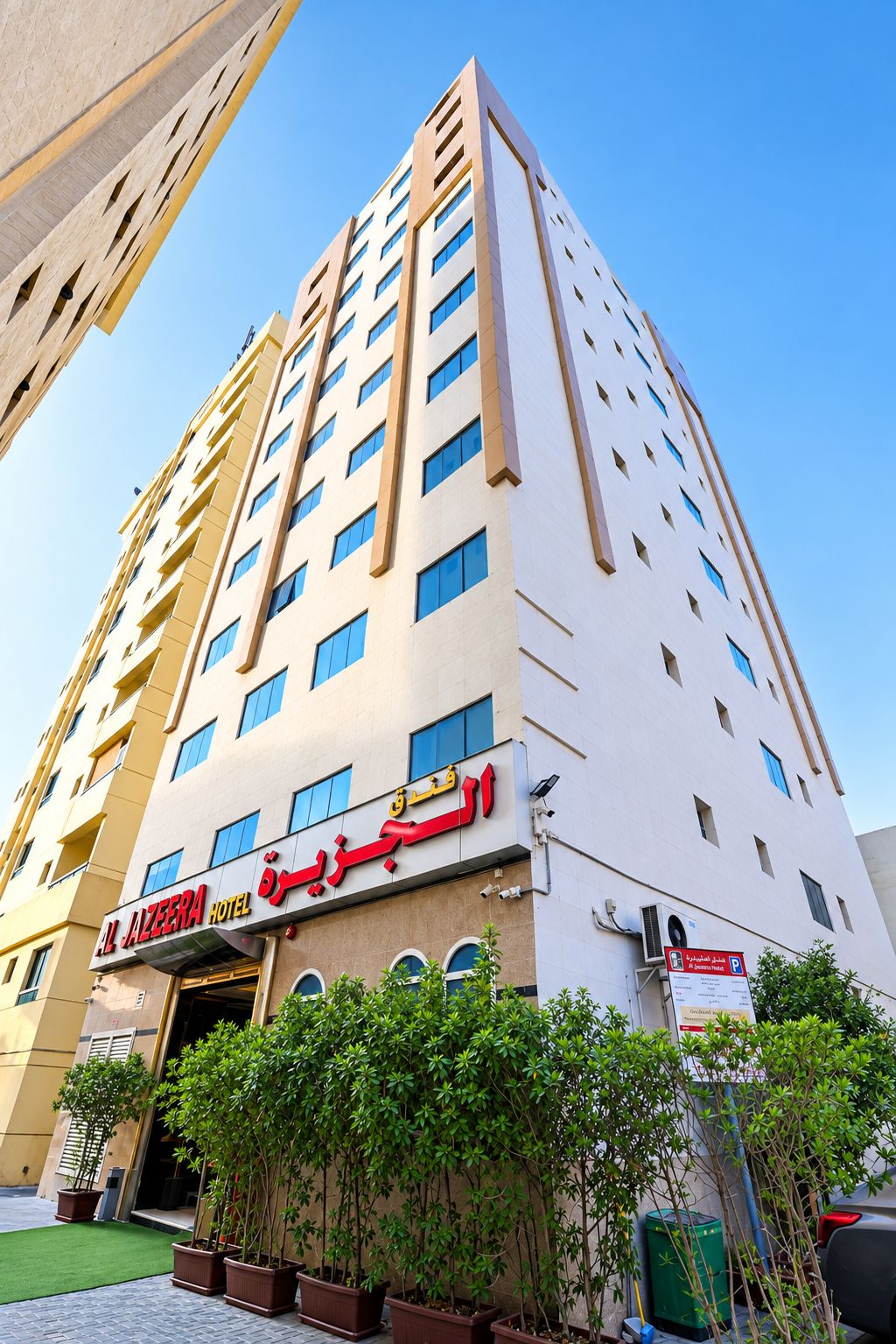 A multi-story hotel with a modern facade, a visible entrance, and a clear sky.