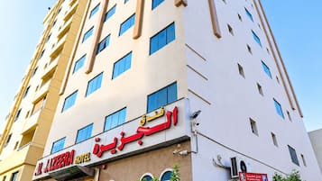 A multi-story hotel with a modern facade, a visible entrance, and a clear sky.