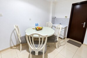 A small dining area with a round table, white chairs, and a fruit basket. - Al Jazeerah Hotel (Sharjah)