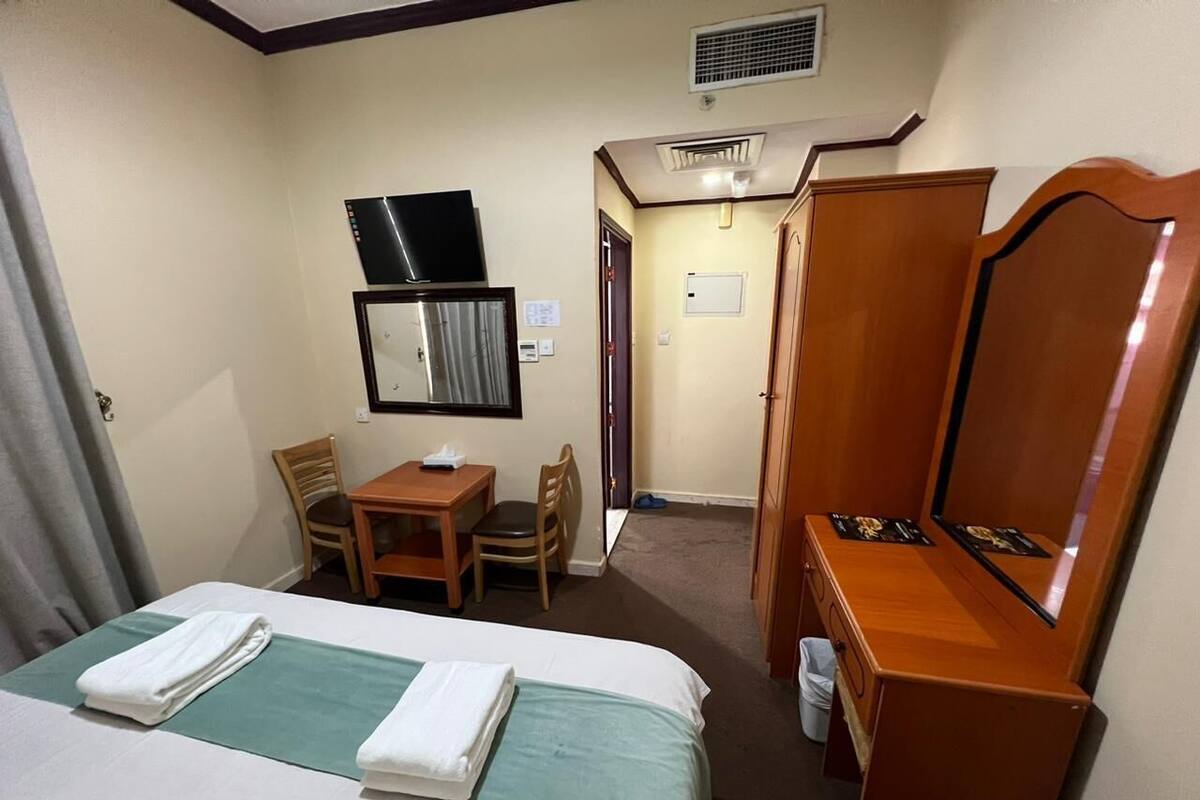 Une chambre d’hôtel comprenant un lit, un bureau, une chaise, un miroir et une armoire.