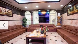 A lobby with a brown sofa set, a coffee table with magazines, and a large window with a view of the city. - Al Jazeerah Hotel (Sharjah)