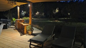 A wooden deck with lounge chairs, a table, and a built-in barbecue grill. - Actaea, Relaxing Villa by the Seashore (Alonissos)
