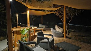 An outdoor patio area with wooden flooring, wicker furniture, and a canopy providing shade. - Actaea, Relaxing Villa by the Seashore (Alonissos)