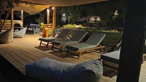 An outdoor deck with lounge chairs, a wooden table, and a barbecue area. - Actaea, Relaxing Villa by the Seashore (Alonissos)