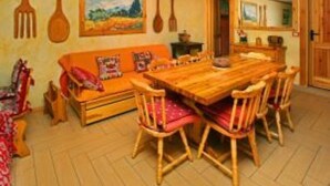 Ein Essbereich mit Holztisch und Stühlen, einer Couch und einem Gemälde an der Wand.