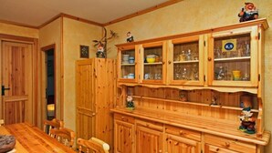 Ein Esszimmer mit Holzboden, einem großen Tisch und Stühlen, Holzkabinette mit Glastüren sowie dekorativen Figuren.