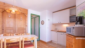 A compact kitchen with wooden cabinets, a microwave, and a dining area with a wooden table and chairs. - Family apartment 6 pers. with balcony in Avoriaz (Avoriaz)
